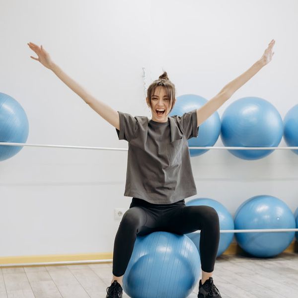 Woman performing a gentle stretching exercise in a bright room.